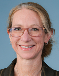 Headshot photograph of a smiling middle-aged woman with glasses, hair pulled back, blue background