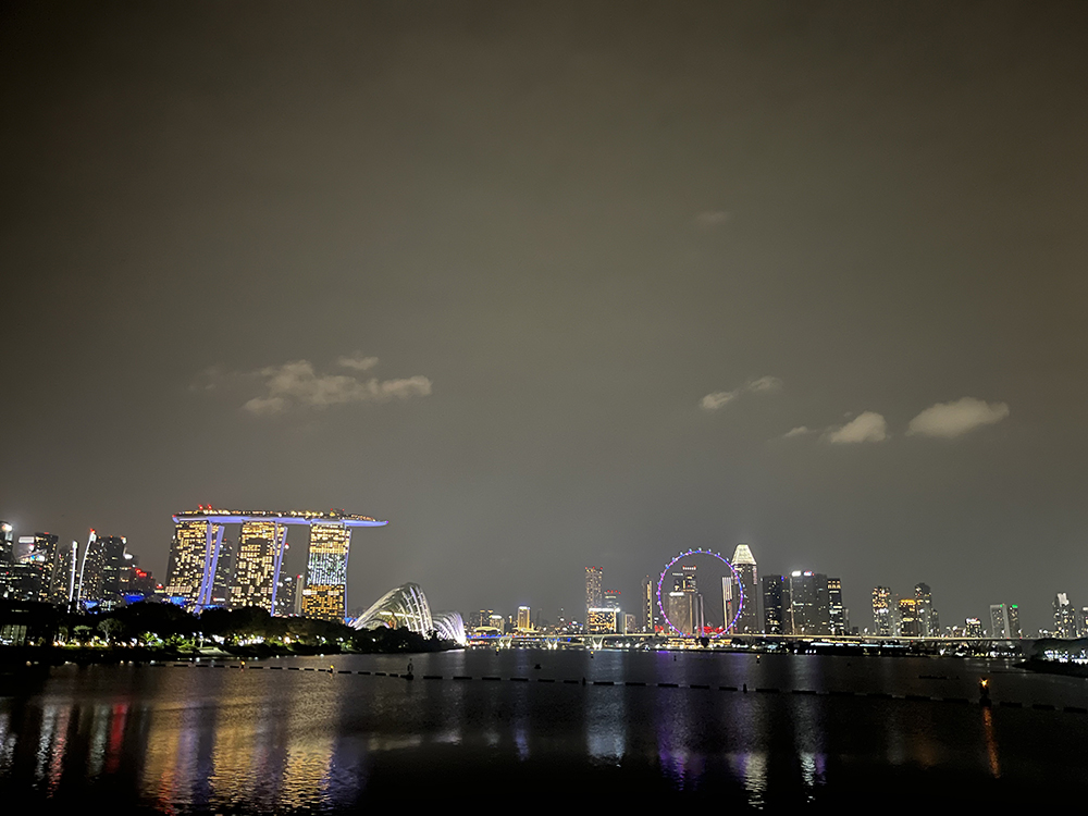 A night skyline with colorful lights of buildings reflected on a lake.