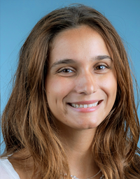 Smiling woman with brown hair, studio headshot against a soft blue background