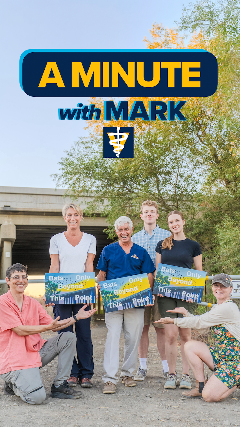 Seven smiling people holding blue signs outdoors; "A Minute with Mark" graphic at top.