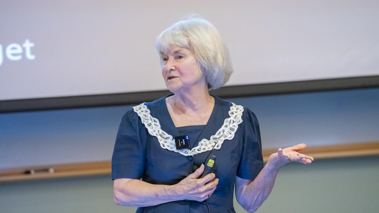 Dr. Lynette Hart standing in front of a screen and podium in a lecture hall.