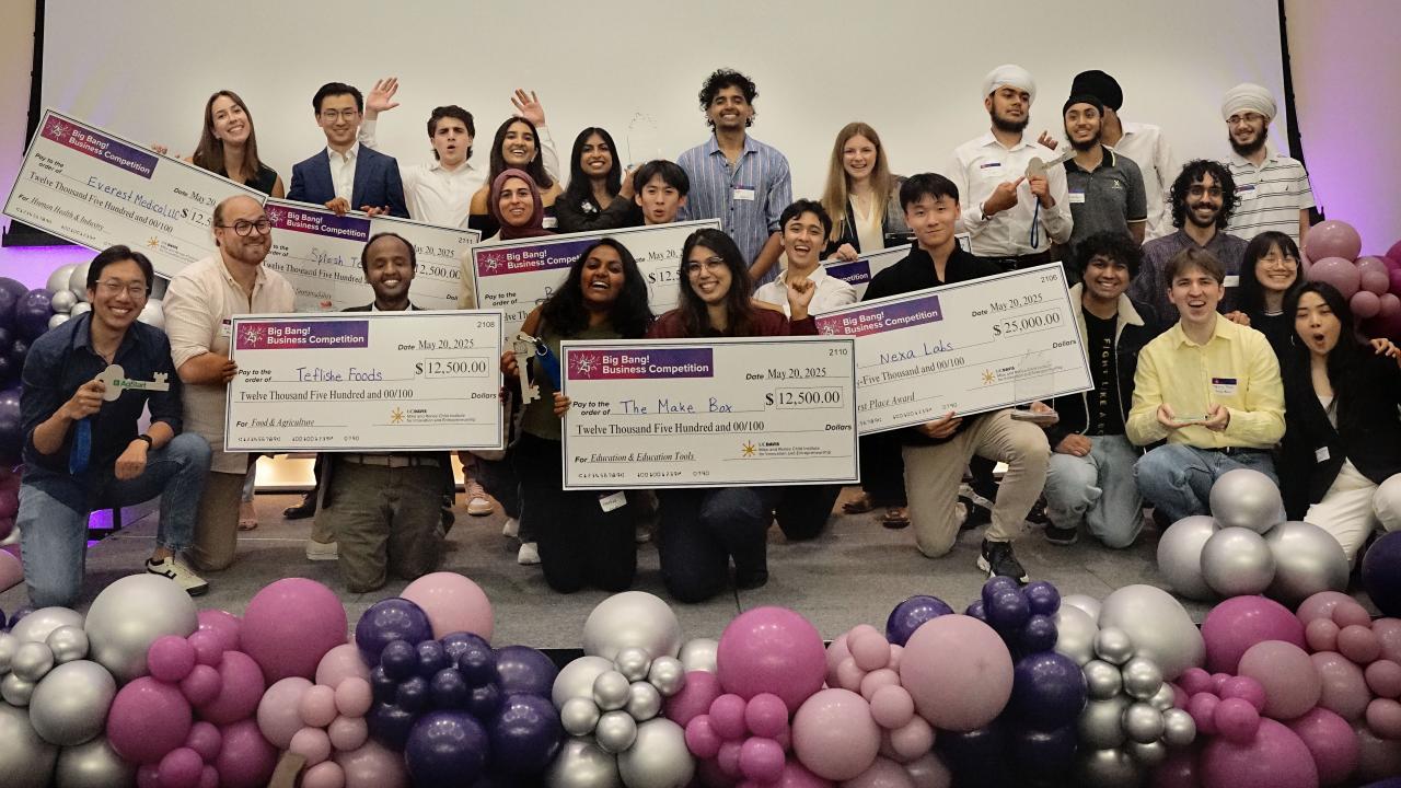 group of students celebrating with balloons and large checks