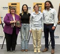 three students being awarded a plaque