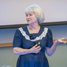 Dr. Lynette Hart standing in front of a screen and podium in a lecture hall.