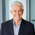 Smiling gray-haired man in suit jacket, corporate office headshot