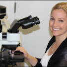 Patty Gaffney at microscope smiles at camera
