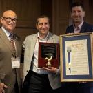 three men with awards at ceremony