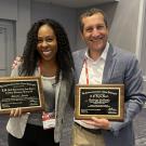 two veterinarians holding plaques representing awards won