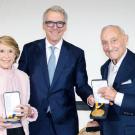 Three people posed holding plaques.