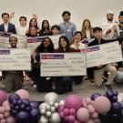 group of students celebrating with balloons and large checks
